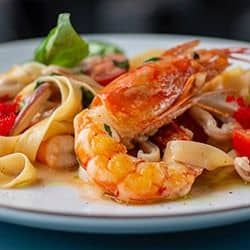 Delicious seafood pasta with shrimp and lobster on a white plate.