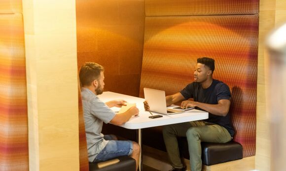 Two men having a business meeting in a modern office booth.