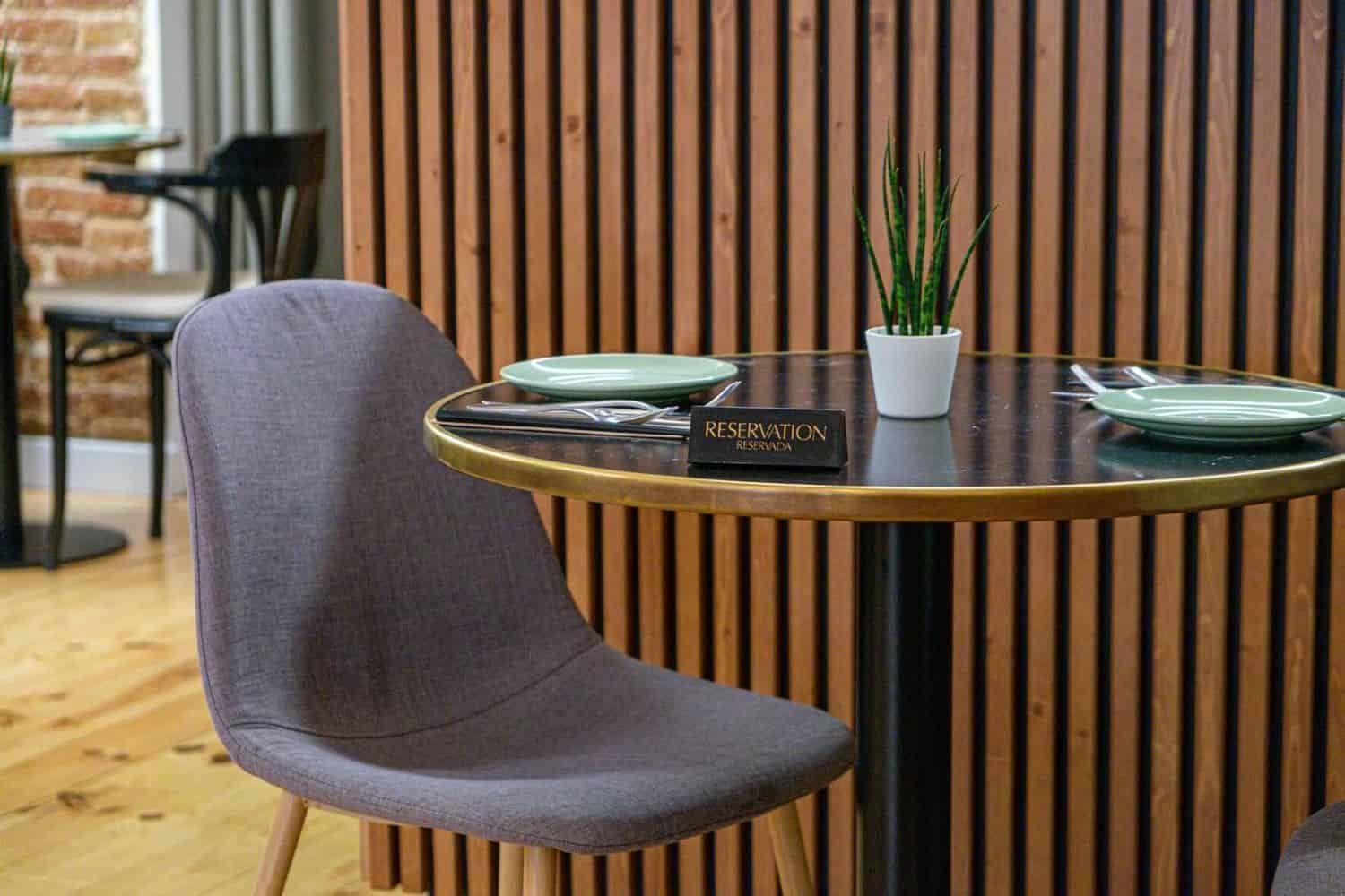 Modern dining area with a round table, gray chair, and decorative plant.