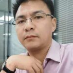 Contact Us 2 Professional man in office wearing glasses and a light purple shirt.